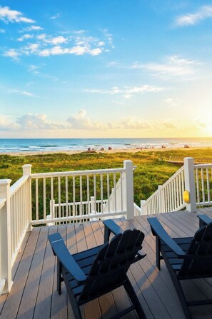 A wooden deck with outdoor seating and a view of the beach. - Top-Rated Beachfront • Steps to Sand • Hot Tub • Elevator • Firepit • Sleeps 16 (Galveston)