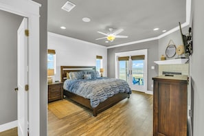 A bedroom with a wooden bed, a ceiling fan, and a view to the outside. - Top-Rated Beachfront • Steps to Sand • Hot Tub • Elevator • Firepit • Sleeps 16 (Galveston)