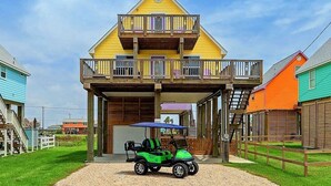 Ein gelbes Haus mit zwei Stockwerken, einem Balkon, einer Veranda und einem Golfwagen vor der Tür.