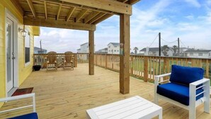 Eine Holzterrasse mit Gartenmöbeln, darunter Stühle und ein Tisch, unter einer Holzpergola.