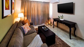 Un salon avec un canapé, une table basse, un téléviseur et une lampe.