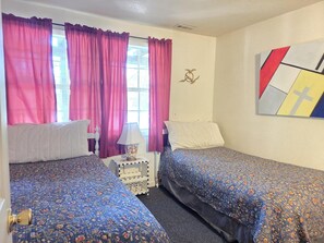 Ein Zimmer mit zwei Betten, einem Nachttisch, einer Lampe und einer Wanddekoration.