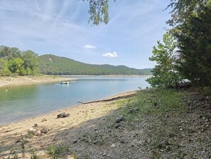 Eine natürliche Landschaft mit einem Fluss, einem Sandstrand und einem bewaldeten Hügel.