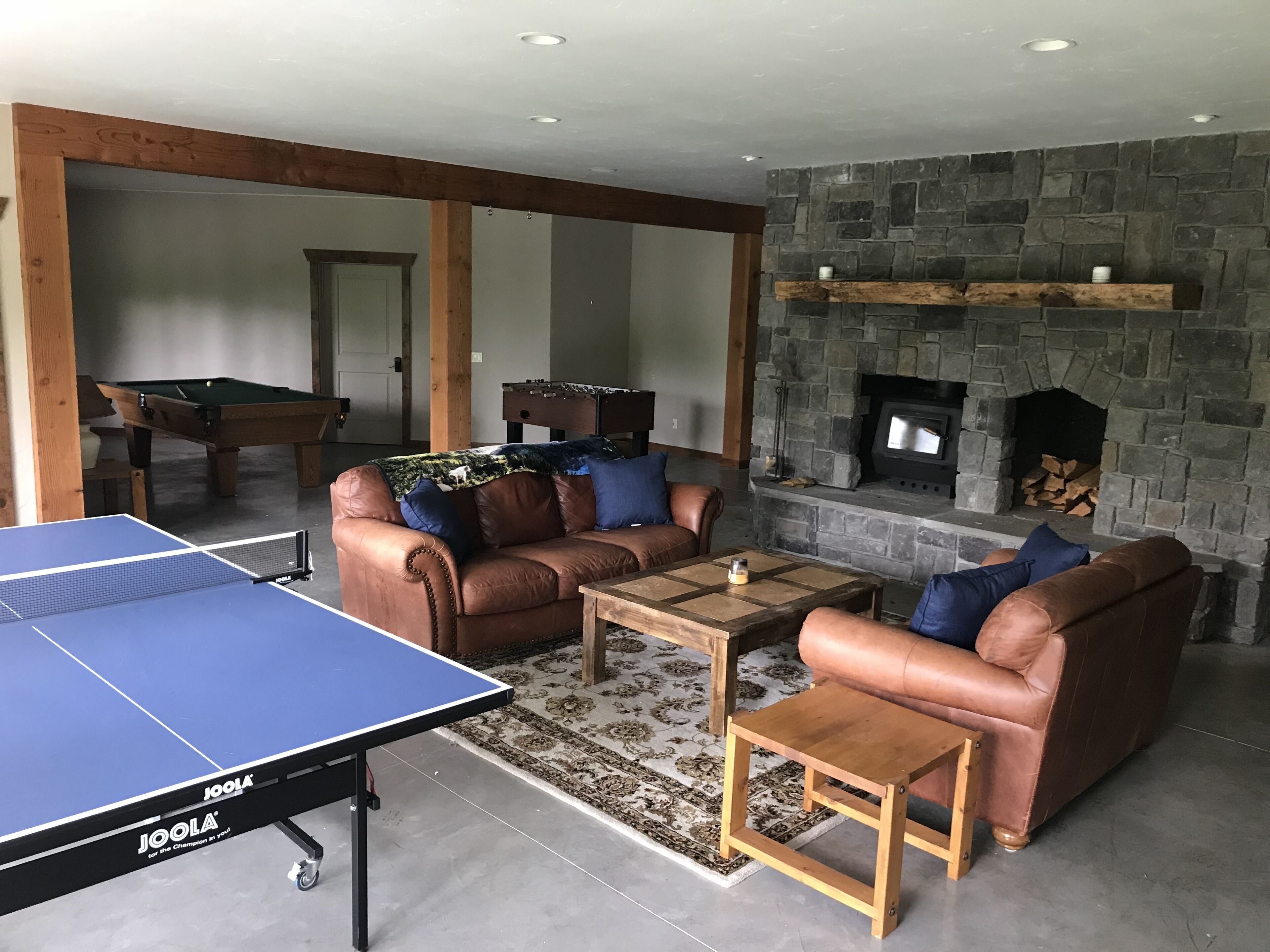 Ein Wohnzimmer mit Tischtennisplatte, Ledersofas, Kamin und Billardtisch.