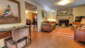 Una sala de estar con chimenea, un sofá, una mesa de centro y un cuadro de un pájaro.