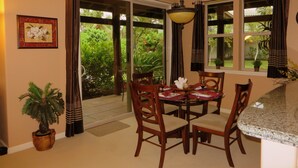 A dining area with a table set for four, surrounded by wooden chairs, a potted plant, and a framed picture on the wall. - Welcome to the Beauty that is Mauna Lani Fairways Unit 1301! (Kamuela)
