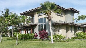 A two-story house with a tiled roof, a balcony, and a well-maintained lawn with various plants. - Welcome to the Beauty that is Mauna Lani Fairways Unit 1301! (Kamuela)