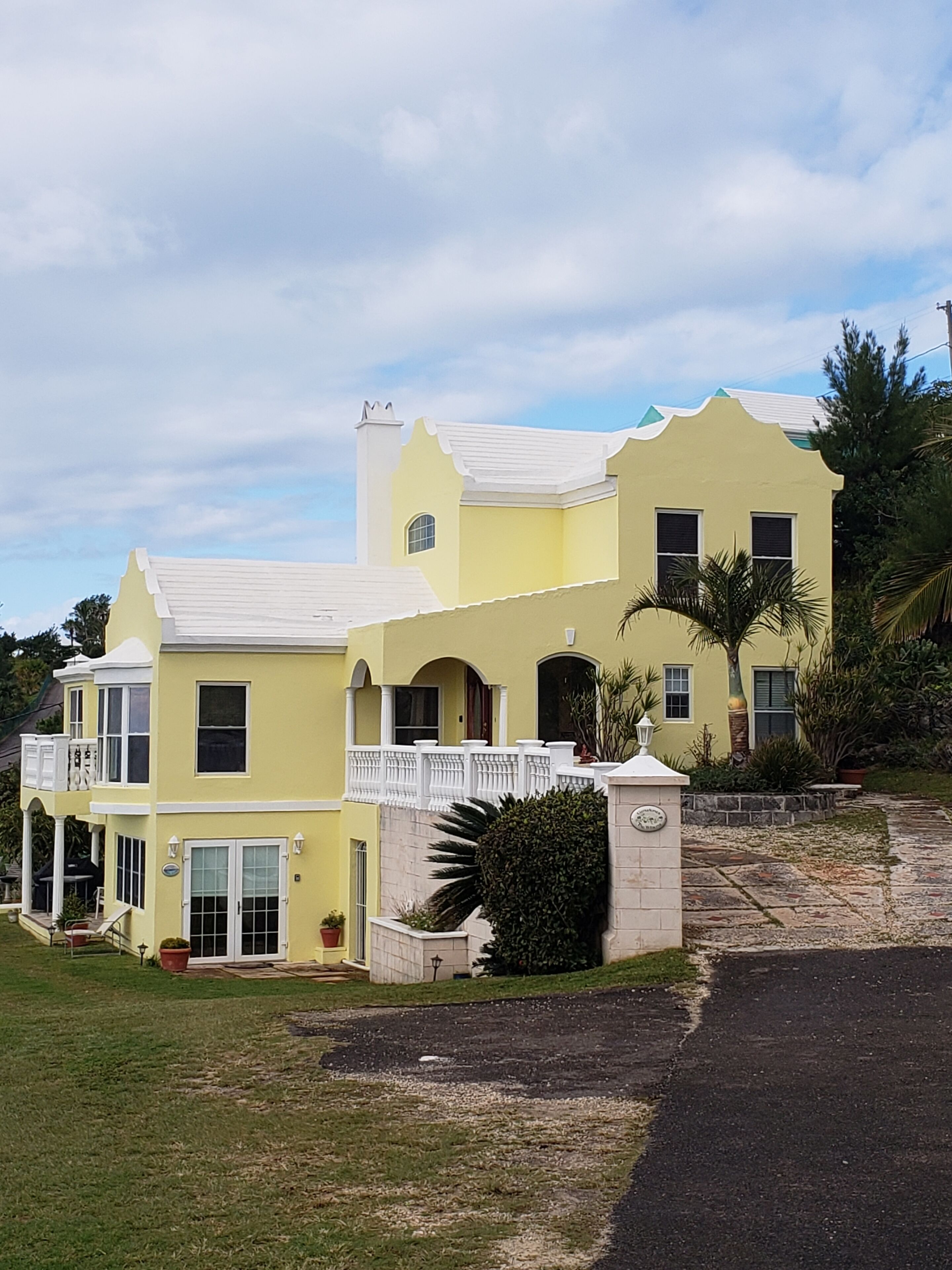 A two-story house with a balcony, a driveway, and a well-maintained lawn.