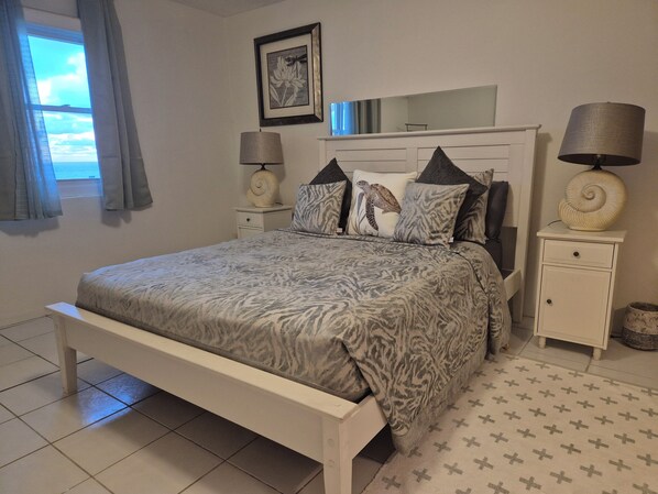 A bedroom with a bed, nightstands, a mirror, and a window with curtains. - Panoramic Private Beachfront Home with Breathtaking Views (Southampton)