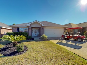 A residential house with a garage, a driveway, and a red golf cart parked in front.