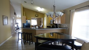 A modern kitchen with a central island, bar stools, and a chandelier. - Starfish -  Private Heated Pool, Walk to Private Beach, GolfCart, Pet Friendly (Miramar Beach)