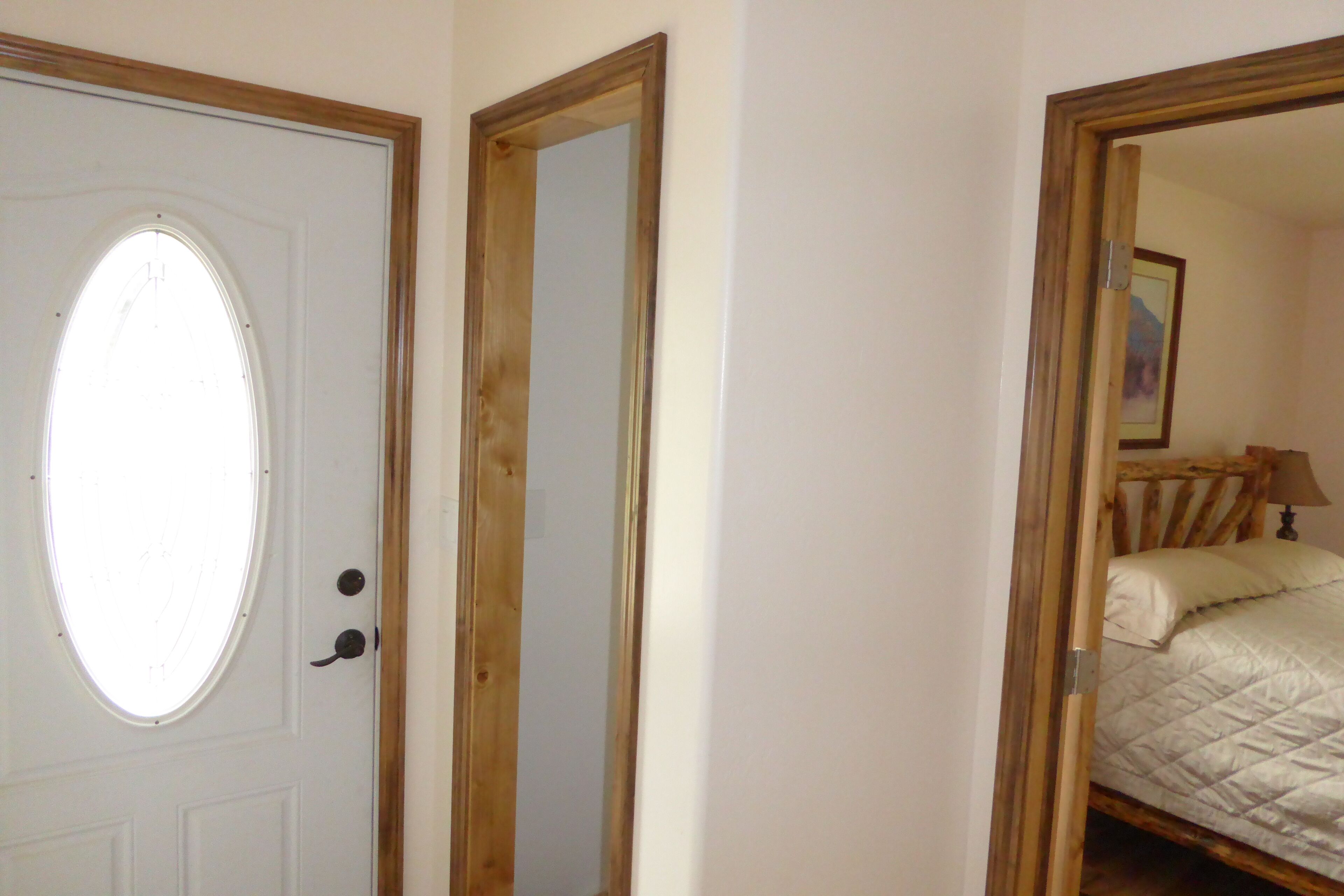 Una habitación con puerta, espejo y cama.