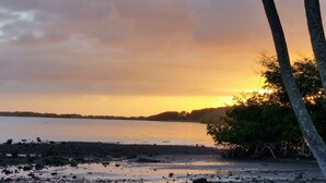 A beach scene with a sunset, calm water, and a distant shoreline. - Peaceful Ocean View. Ground Floor. Classy, clean and quiet. (Kaunakakai)