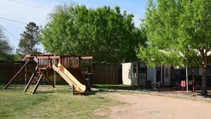 A playground with a slide and climbing structure, a small building labeled "OFFICE", and a gravel path.