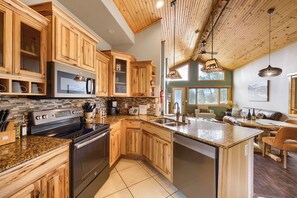 A modern kitchen with wooden cabinets, a stainless steel stove, and a granite countertop. - Pikes Peak Ranch - Bear Den Cabin (Woodland Park)