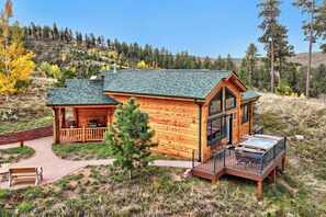 A log cabin with a deck, a covered porch, and a hot tub.