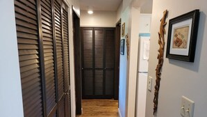 Un couloir avec un plancher en bois, un réfrigérateur et un interrupteur fixé au mur.