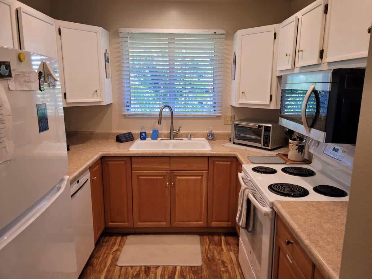 A compact kitchen with wooden cabinets, a sink, a microwave, and a stove.