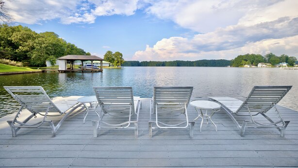 A wooden dock with four lounge chairs and a small table, overlooking a calm lake with a gazebo and trees in the background. - Peaceful Lakefront, Spectacular View, Spacious 2 Level, 30 Min from Auburn (Alexander City)