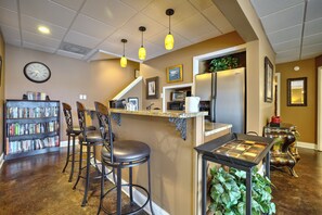 Une cuisine avec un coin bar, une bibliothèque et une horloge au mur.