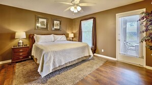 A bedroom with a bed, two bedside tables, a ceiling fan, and a window with blinds. - Peaceful Lakefront, Spectacular View, Spacious 2 Level, 30 Min from Auburn (Alexander City)