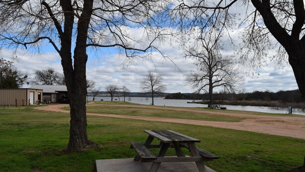 A picnic table in a park with a lake in the background. - Cabin at Texas Hills RV Haven on Lake Buchanan (Tow)
