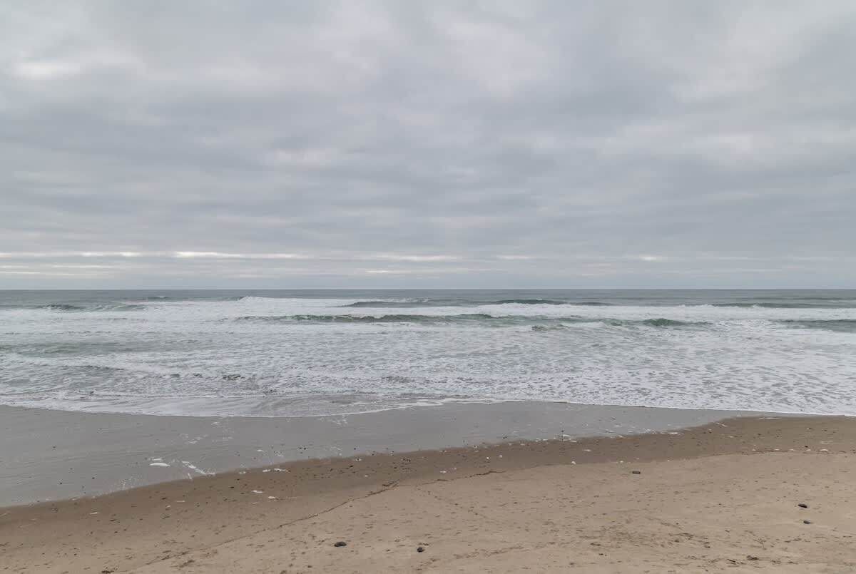 Uma praia com ondas e céu nublado.