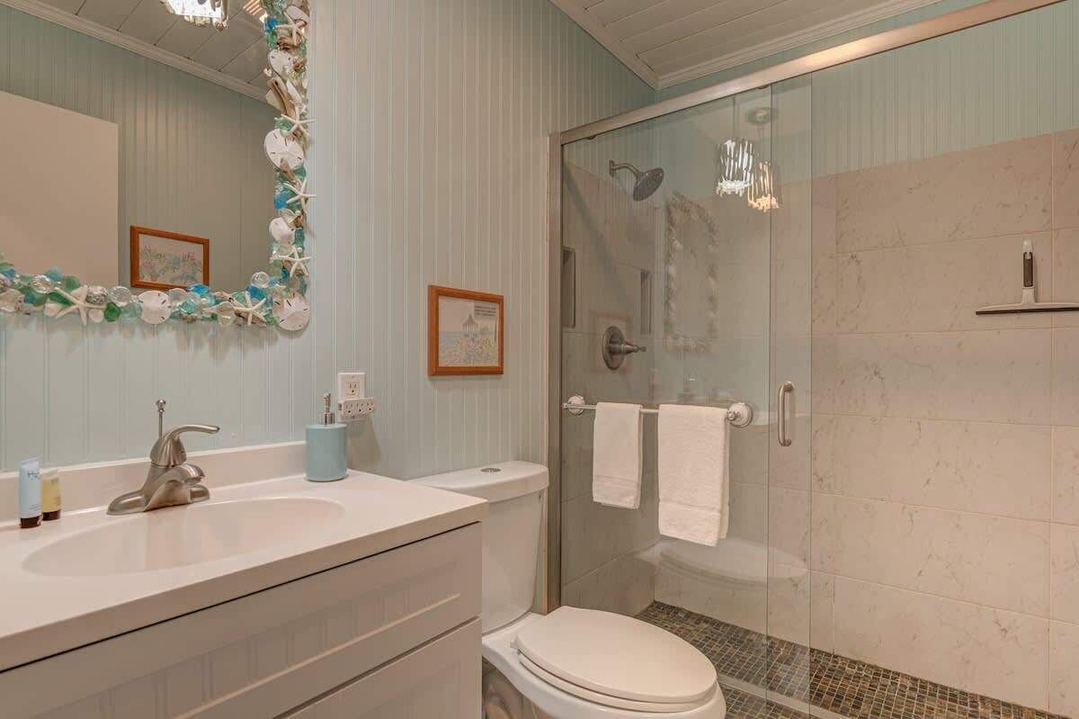Ein Badezimmer mit Duschkabine aus Glas, Waschbecken mit Spiegel und Toilette.
