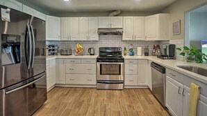 Una cocina moderna con gabinetes blancos, electrodomésticos de acero inoxidable y salpicadero de azulejos.