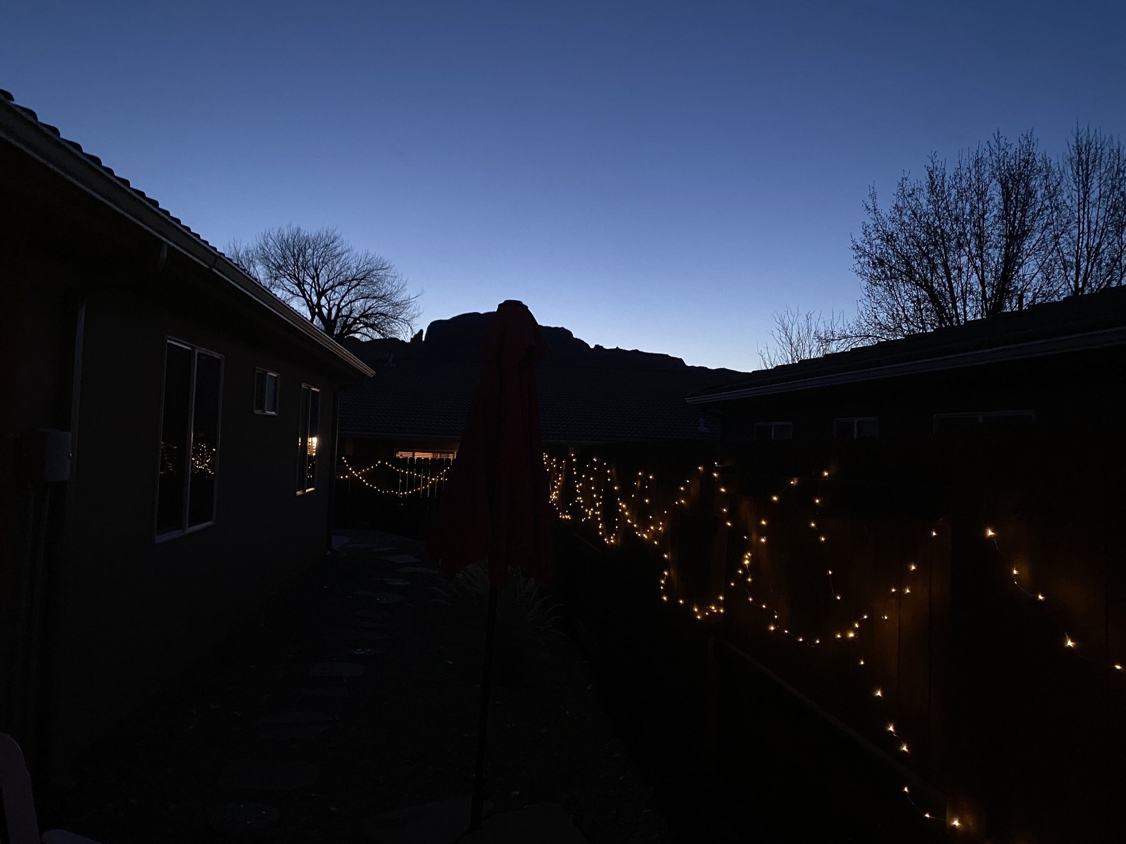 A residential area at dusk with houses and a mountain in the background.