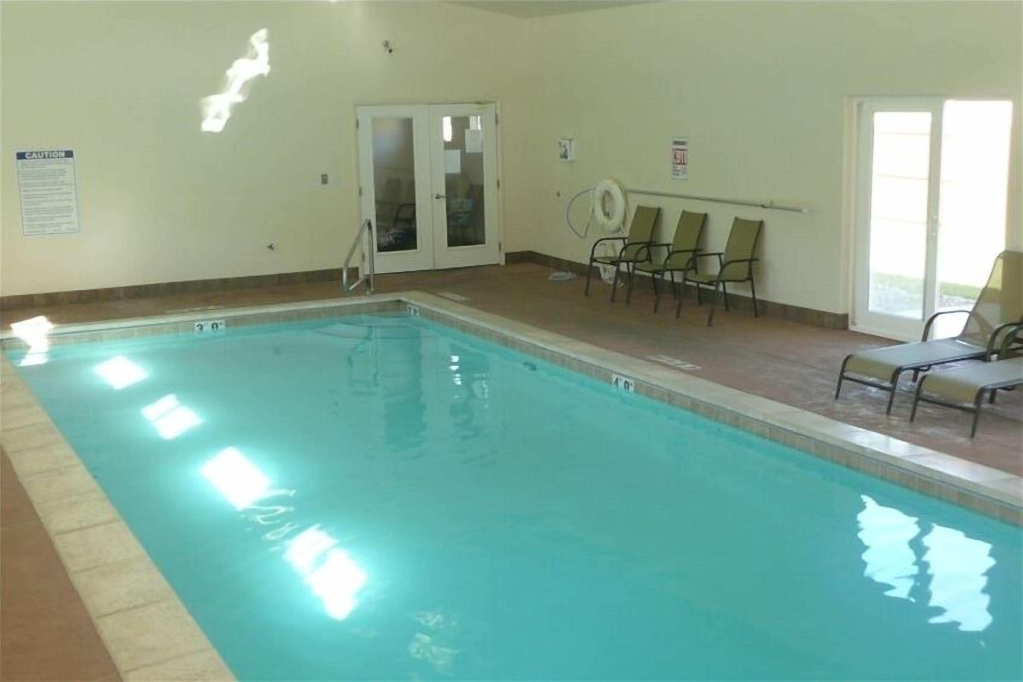 A swimming pool with a glass door, chairs, and a caution sign.