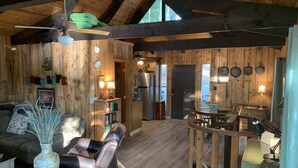 A cozy cabin interior with a wooden interior, a dining area, and a living room with a sofa and a vase.