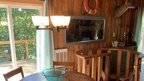 A wooden dining area with a round table, chairs, and a glass bowl centerpiece.