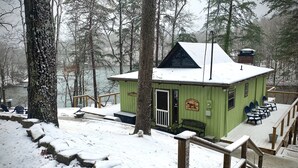 A green lodge with a wooden deck and a view of the lake.