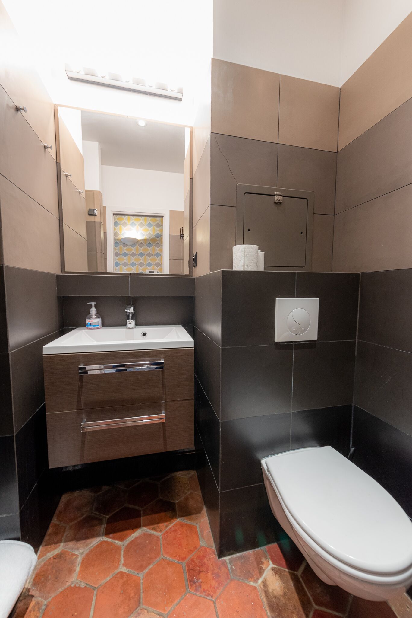 Un baño con un lavamanos moderno, espejo y retrete.