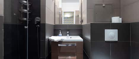 Un baño moderno con ducha de vidrio, lavamanos con toalla y retrete.