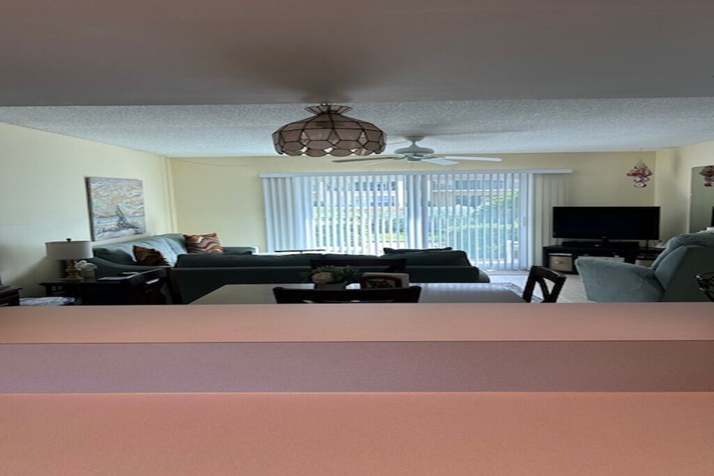 Ein Wohnzimmer mit einer Sofagarnitur, einem Couchtisch, einem Fernseher und einem Deckenventilator.