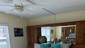 Een slaapkamer met een bed, een plafondventilator, een grote spiegel en een raam.