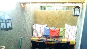 A small patio area with a table and chairs, a cushioned bench, and potted cacti.