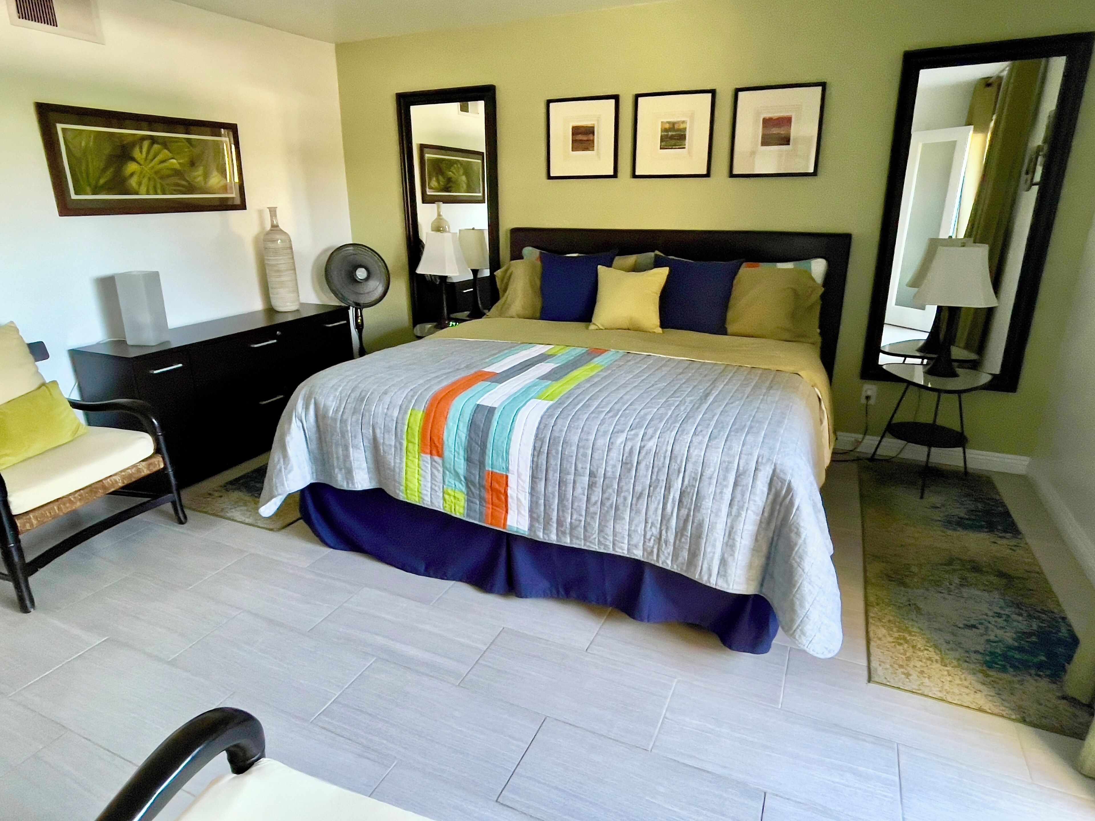 A bedroom with a bed, bedside tables, a chair, a dresser, and framed pictures on the wall.