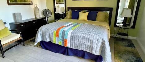 A bedroom with a bed, bedside tables, a chair, a dresser, and framed pictures on the wall.