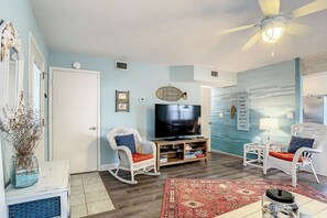 Relax in this inviting living room with a large flat-screen TV, comfortable seating, and a cozy rug.