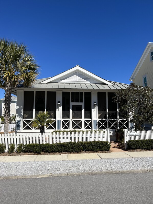 A two-story building with a white picket fence, a covered porch, and a clear blue sky. - "Summer Magic" in Carillon Beach - RENOVATED! (Sunnyside)