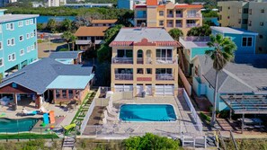 Un hotel de varios pisos con piscina en la azotea, balcones y vistas del entorno.
