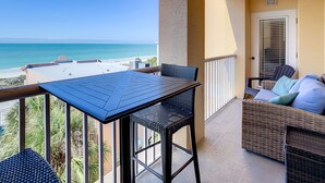 Een balkon met een tafel en stoelen, met uitzicht op het strand.