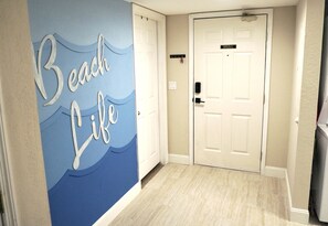 Ein Flur mit einem Wandgemälde mit dem Titel 'Beach Life', einer weißen Tür und einem hellen Boden.