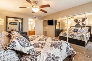 Cozy retreat with a large bed, flat-screen TV, and ceiling fan.