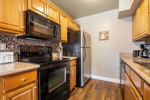 Enjoy cooking in this well-equipped kitchen with a range hood, refrigerator, microwave, and stove.