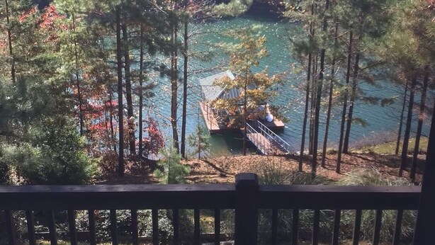 A view from a wooden deck overlooking a lake surrounded by trees.