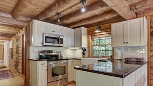 A log cabin kitchen with a central island, built-in microwave, stainless steel appliances, and wooden cabinetry.